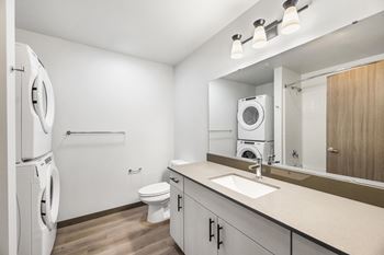 a white bathroom with a washer and dryer in it and a white toilet